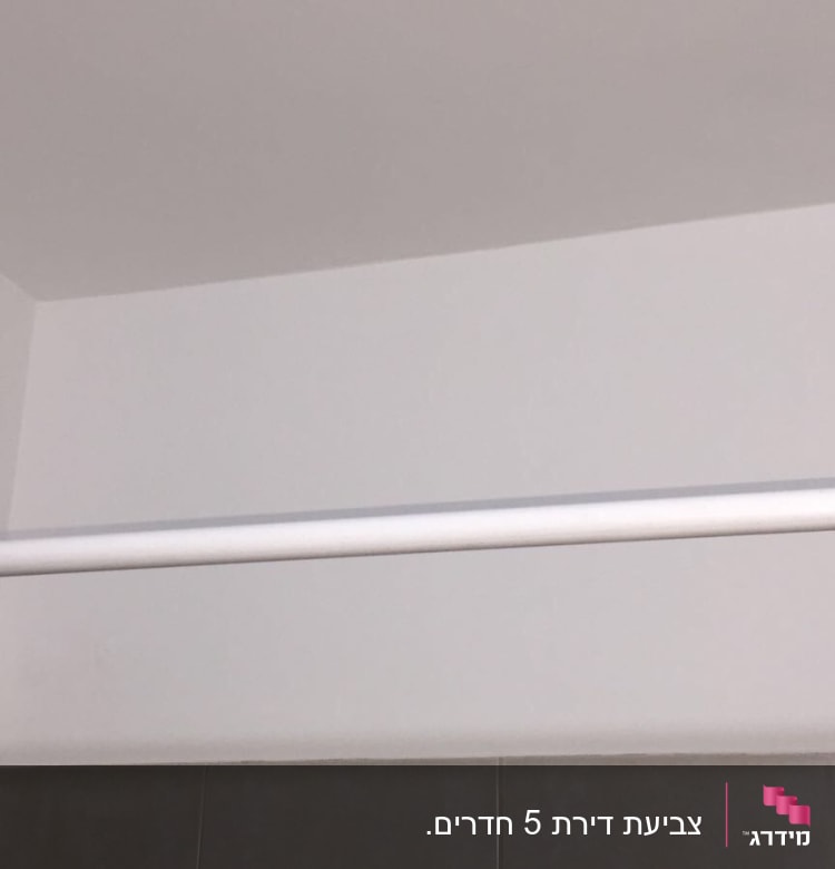 קיר צבוע בלבן עם מוט תלייה לבן